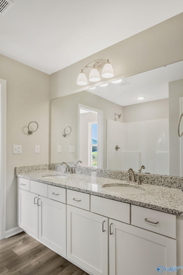 bathroom with double vanity, visible vents, a shower, and a sink