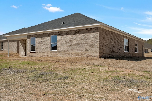 back of house with brick siding and a shingled roof