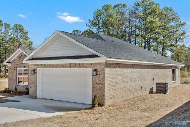 view of home's exterior with cooling unit, driveway, roof with shingles, a garage, and brick siding