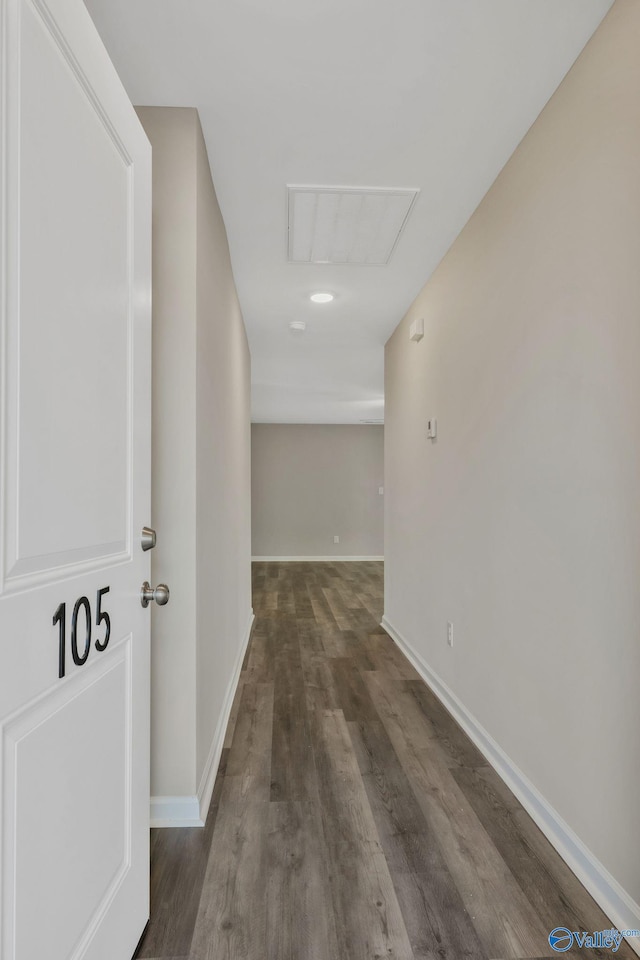 hall featuring visible vents, baseboards, and wood finished floors