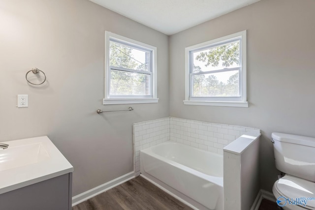 bathroom featuring wood-type flooring, vanity, a tub to relax in, and toilet