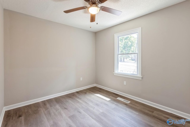 unfurnished room with ceiling fan, a textured ceiling, and light wood-type flooring