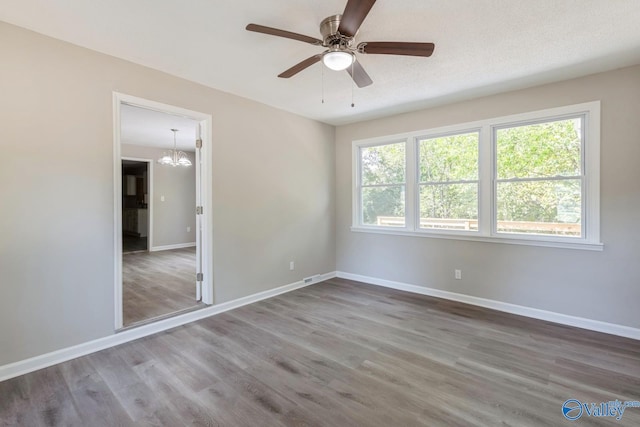 unfurnished bedroom featuring hardwood / wood-style floors, ceiling fan with notable chandelier, and a textured ceiling