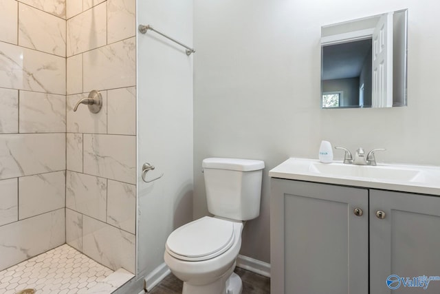 bathroom with a tile shower, vanity, and toilet