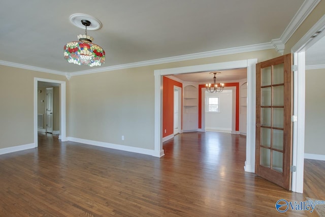 spare room featuring baseboards, dark wood-type flooring, a notable chandelier, and ornamental molding