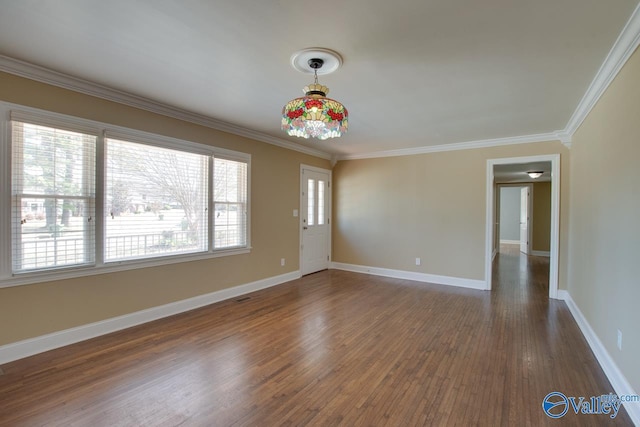 empty room featuring dark wood finished floors, visible vents, crown molding, and baseboards