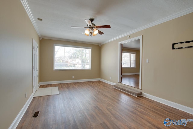 spare room featuring visible vents, ceiling fan, baseboards, ornamental molding, and wood finished floors