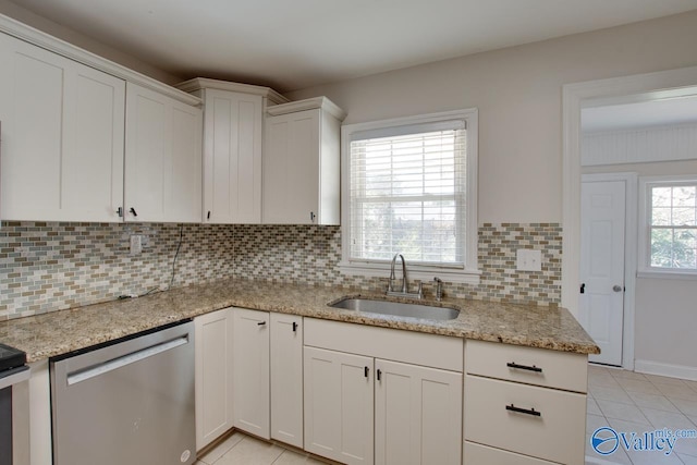 kitchen featuring dishwasher, white cabinets, light tile patterned floors, and a sink