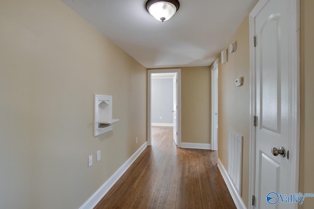 hallway featuring visible vents, baseboards, and wood finished floors