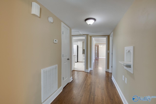 hallway featuring visible vents, dark wood-type flooring, and baseboards