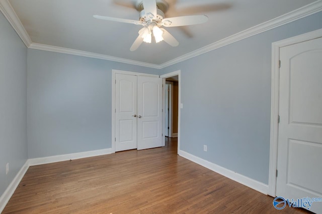 empty room with ornamental molding, baseboards, and wood finished floors