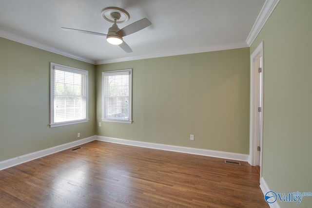 unfurnished room featuring visible vents, crown molding, baseboards, wood finished floors, and a ceiling fan