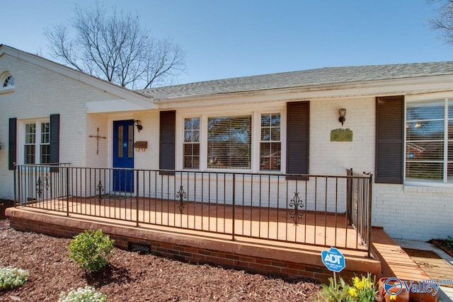 exterior space with brick siding, a porch, and roof with shingles