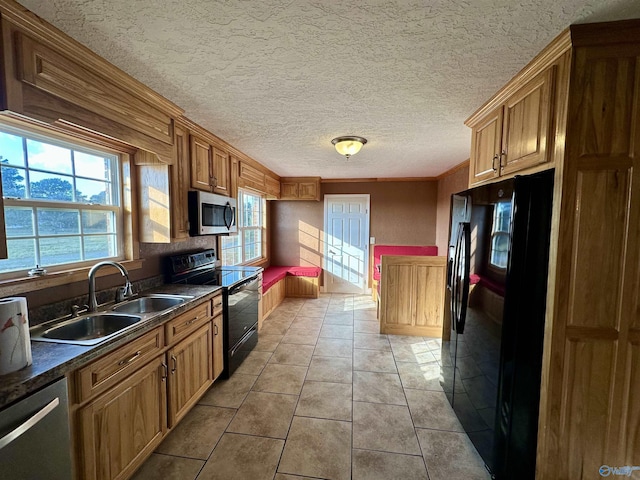 kitchen with sink, crown molding, a textured ceiling, light tile patterned floors, and black appliances