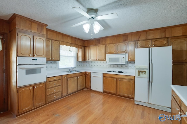 kitchen featuring white appliances, sink, light hardwood / wood-style flooring, ceiling fan, and tasteful backsplash