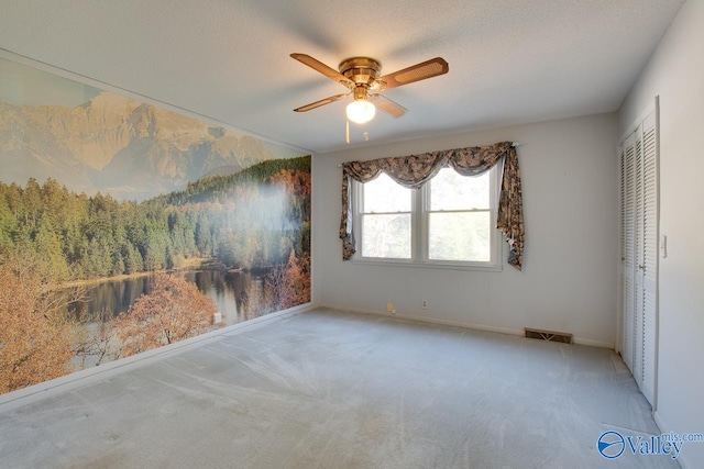 unfurnished bedroom with ceiling fan, a closet, light colored carpet, and a textured ceiling