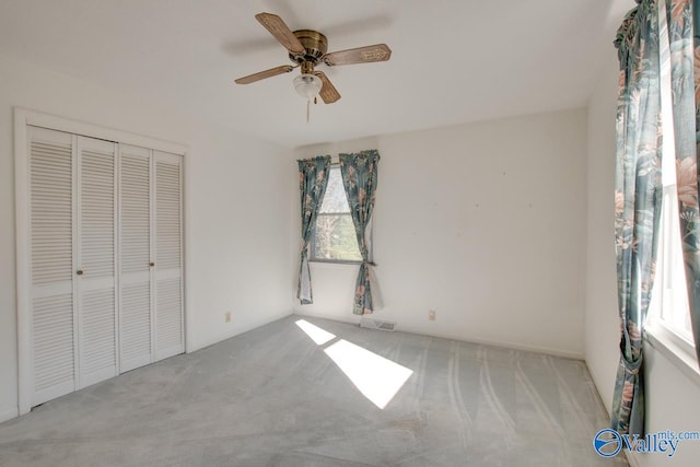 unfurnished bedroom featuring ceiling fan, light colored carpet, and a closet