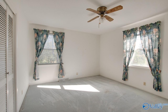 unfurnished bedroom featuring ceiling fan, light colored carpet, and a closet