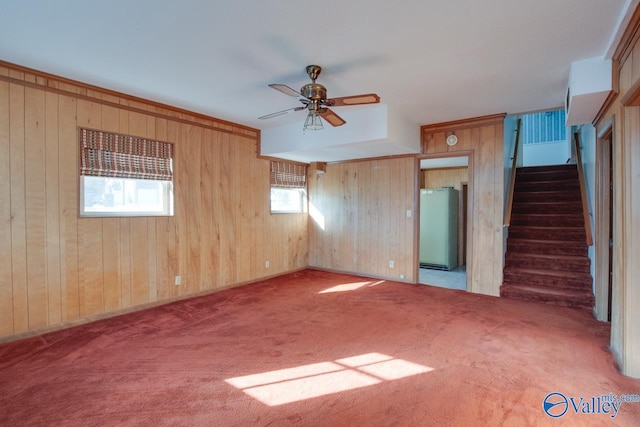 carpeted spare room featuring ceiling fan and wood walls