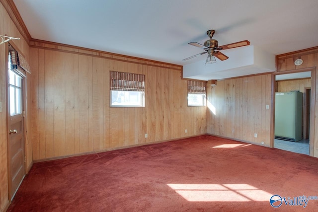 carpeted empty room featuring ceiling fan and wooden walls