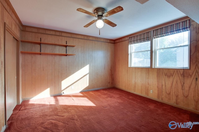 carpeted empty room with ceiling fan and wooden walls