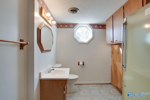 bathroom featuring a textured ceiling, vanity, and toilet