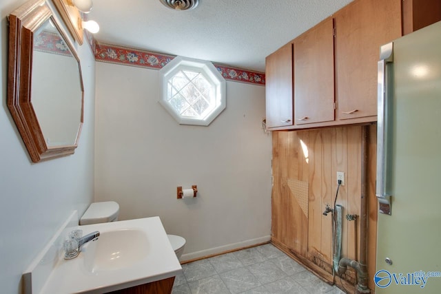 bathroom featuring vanity, toilet, and a textured ceiling