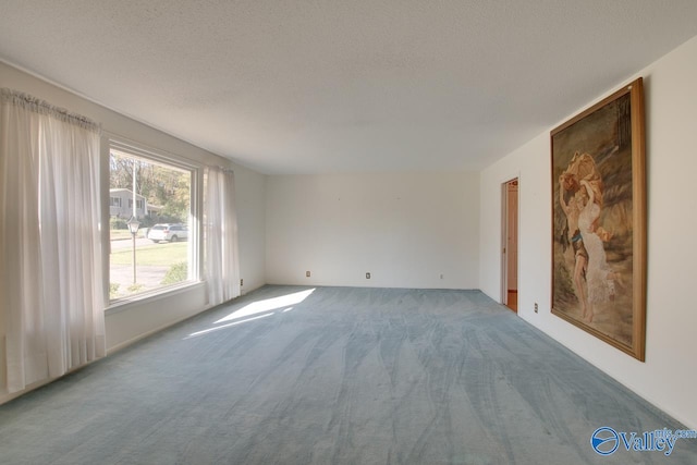 carpeted empty room with a textured ceiling