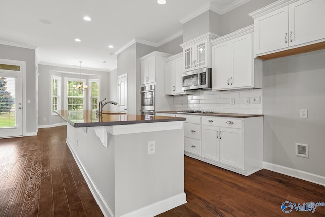 kitchen with sink, a kitchen island with sink, white cabinetry, stainless steel appliances, and decorative backsplash