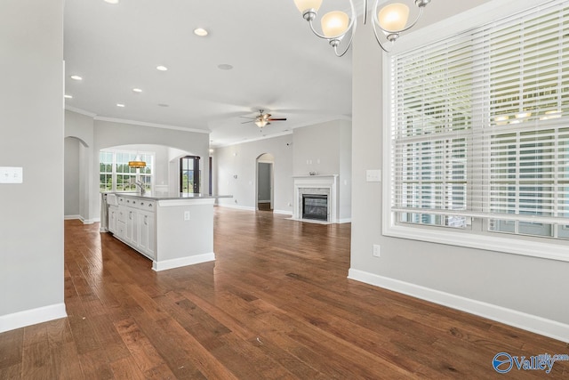 kitchen with a kitchen island with sink, white cabinetry, dark hardwood / wood-style flooring, and ornamental molding