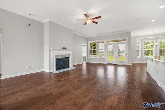 unfurnished living room with ceiling fan with notable chandelier, ornamental molding, and dark hardwood / wood-style floors