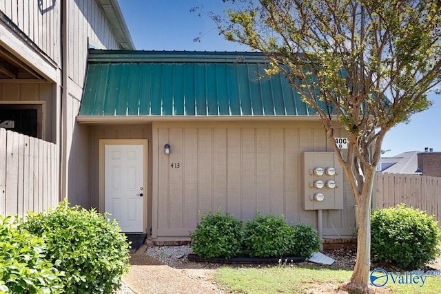 property entrance with metal roof, fence, and a standing seam roof