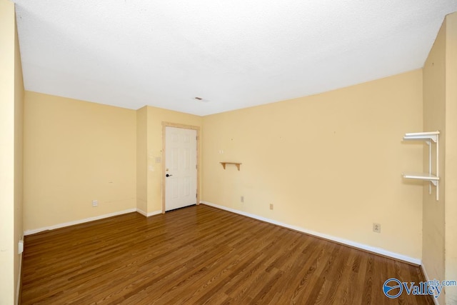 spare room featuring wood finished floors and baseboards