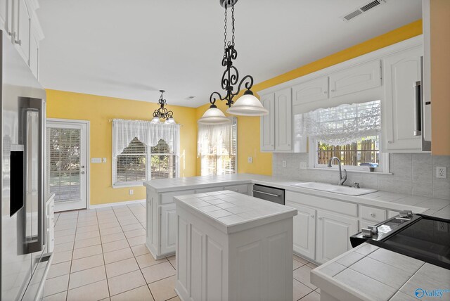 kitchen with tasteful backsplash, a center island, tile countertops, and white cabinets