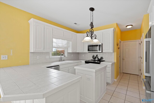 kitchen featuring appliances with stainless steel finishes, sink, hanging light fixtures, and white cabinetry