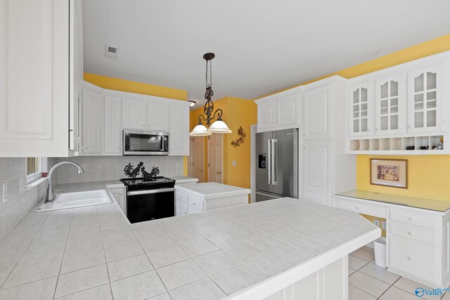 kitchen featuring white cabinets, kitchen peninsula, sink, decorative light fixtures, and stainless steel appliances