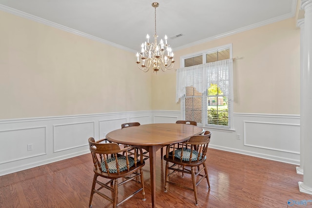 dining room with decorative columns, crown molding, an inviting chandelier, and wood-type flooring