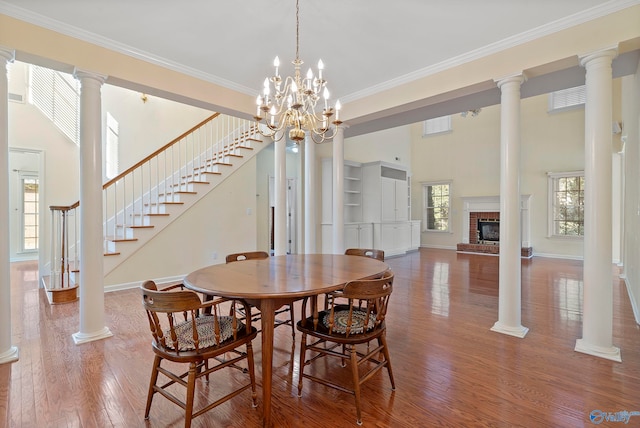 dining space featuring hardwood / wood-style flooring, a fireplace, a towering ceiling, and ornamental molding