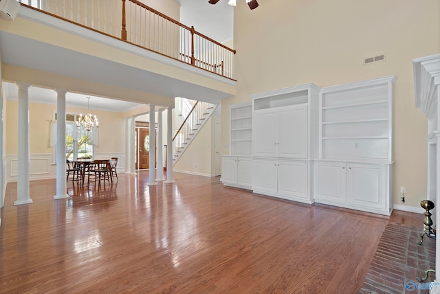 living room featuring built in shelves, ceiling fan with notable chandelier, hardwood / wood-style floors, and a high ceiling