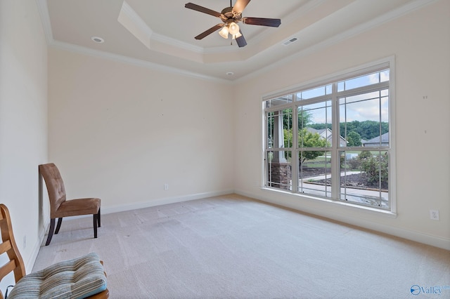 unfurnished room featuring a raised ceiling, ceiling fan, ornamental molding, and light carpet