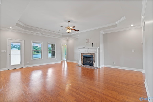 unfurnished living room with light hardwood / wood-style flooring, ceiling fan, ornamental molding, and a stone fireplace