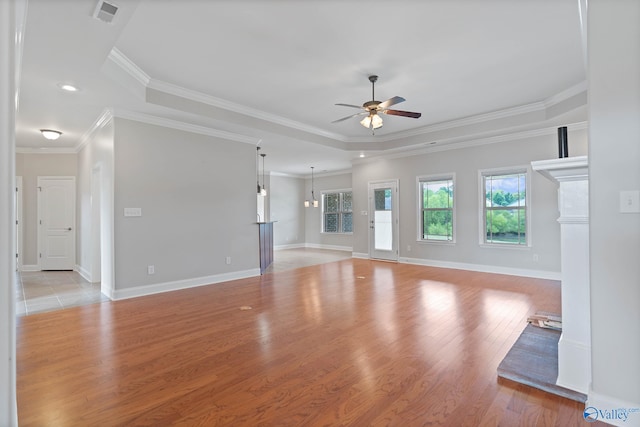 unfurnished living room featuring crown molding, a tray ceiling, ceiling fan, and light hardwood / wood-style floors