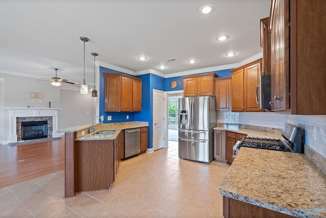 kitchen with light stone countertops, a fireplace, stainless steel appliances, kitchen peninsula, and ceiling fan