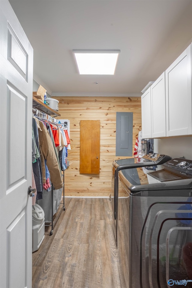 washroom with separate washer and dryer, light hardwood / wood-style flooring, electric panel, and cabinets