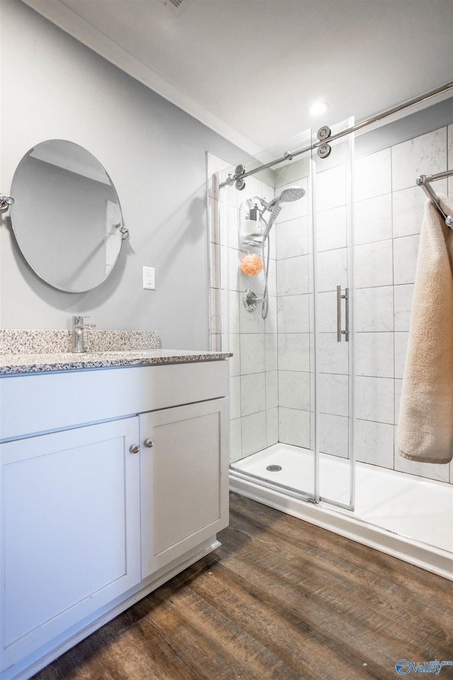 bathroom with hardwood / wood-style flooring, vanity, a shower with door, and ornamental molding