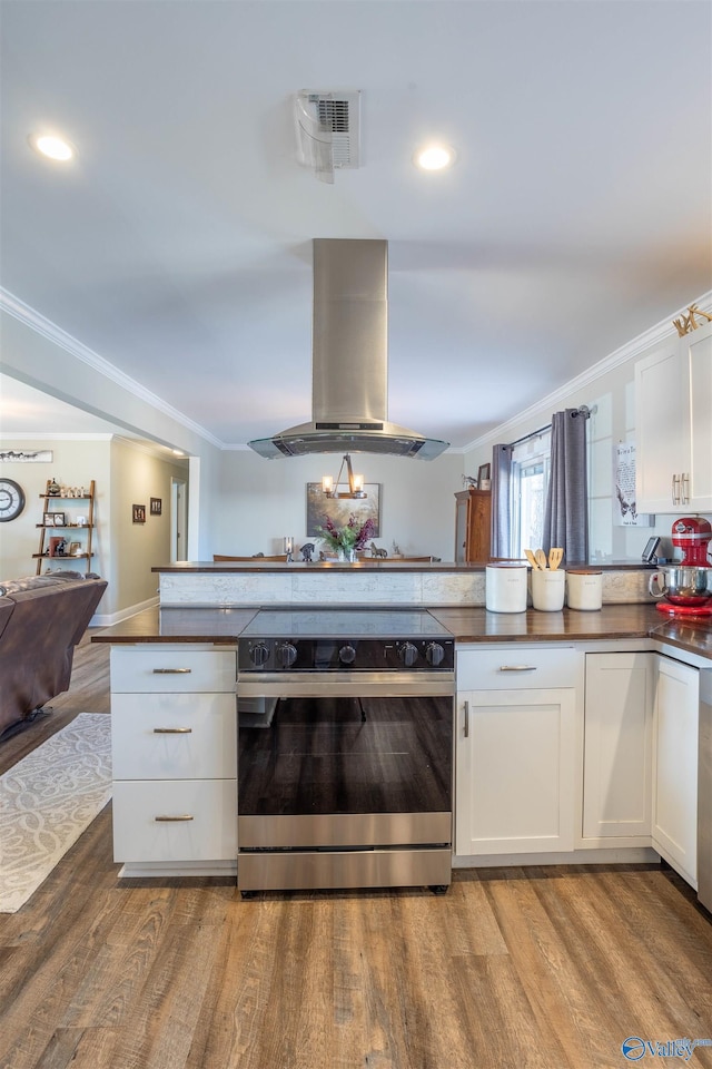 kitchen featuring stainless steel electric range oven, light hardwood / wood-style flooring, kitchen peninsula, island exhaust hood, and white cabinets