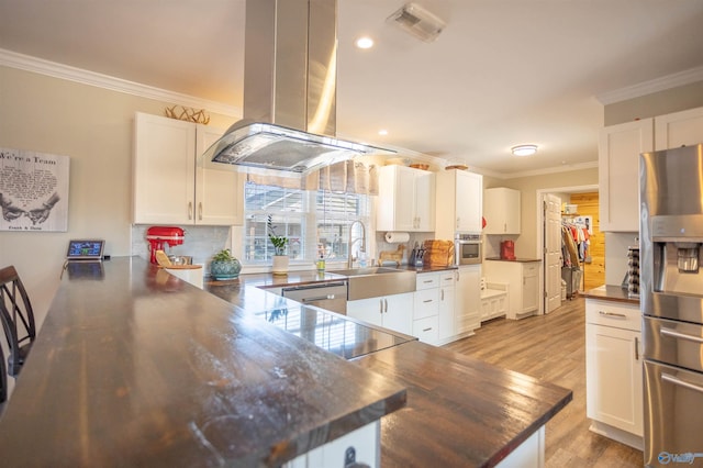 kitchen with sink, white cabinetry, island range hood, appliances with stainless steel finishes, and kitchen peninsula