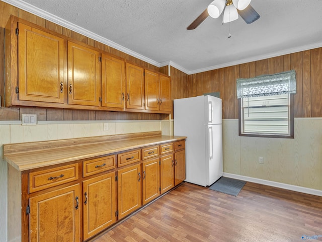 17441 E Limestone Rd, Athens, AL 35613 - kitchen featuring freestanding refrigerator, brown cabinets, a ceiling fan, light wood finished floors, and wooden walls