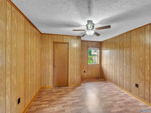 17441 E Limestone Rd, Athens, AL 35613 - spare room with wood finished floors, ceiling fan, baseboards, wooden walls, and a textured ceiling