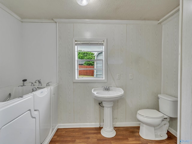 17441 E Limestone Rd, Athens, AL 35613 - bathroom with wood finished floors, toilet, baseboards, a bath, and a textured ceiling